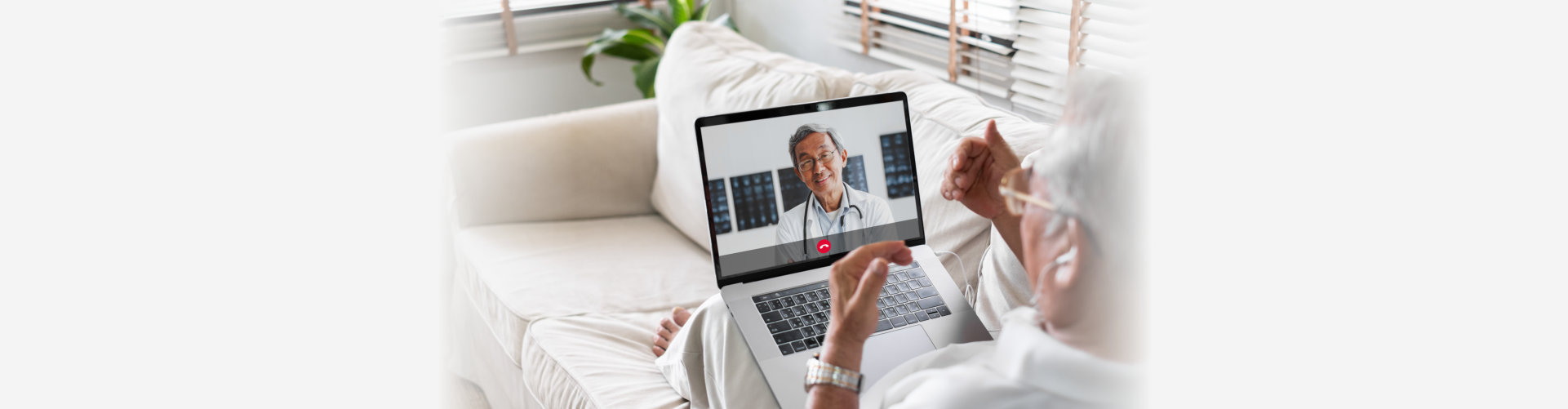 Elderly man talking to his doctor online using his laptop