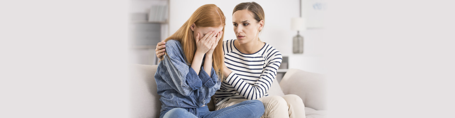 Young depressed women crying being comforted by friend at home